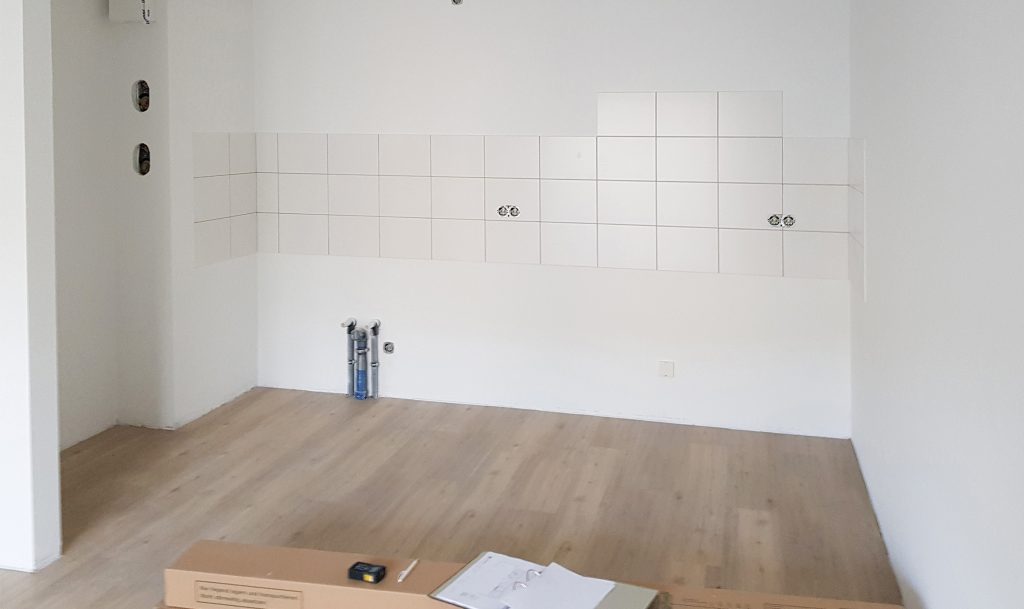 Leerstehende Küche, frisch gestrichen mit Fliesenschild. Ein Aufmaß wird genommen.