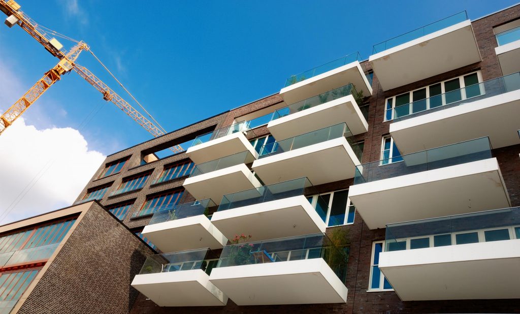 Modernisierungsprojekt Wohnungsbau mit Küchen von Hummel. Klinkerbau vor blauem Himmel und Krahn.